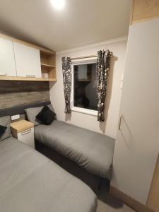 a small bedroom with two beds and a window at Hillingworth's Hot Tub Retreat - Lochmaben in Dumfries