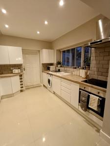 a kitchen with white cabinets and a washer and dryer at The Tansley Gardens in Darlington