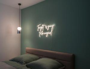 Cette chambre comprend un lit et un panneau de néon sur le mur. dans l'établissement bevoflats - Stilvolles Souterrain am Mehringdamm, à Berlin