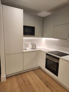 a kitchen with white cabinets and a stove top oven at Stunning 2-Bed Apartment in Brentford in Brentford