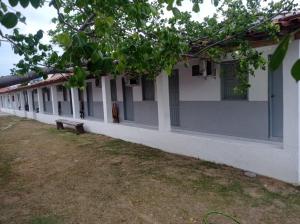 a row of buildings with a person sitting on a bench at POUSADINHA LITORAL in Mucuri