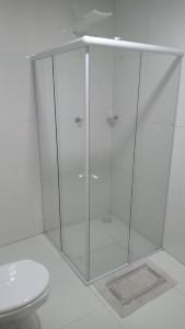 a shower with a glass door next to a toilet at POUSADINHA LITORAL in Mucuri