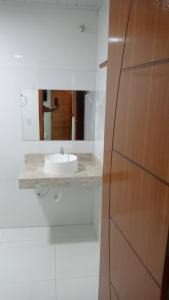 La salle de bains blanche est pourvue d'un lavabo et d'un miroir. dans l'établissement POUSADINHA LITORAL, à Mucuri