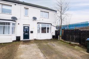 una casa blanca con una puerta negra y una valla en Flat in west midlands en Longford