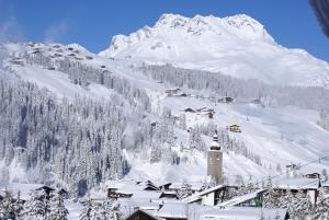 a mountain covered in snow with a village in the foreground at Hotel Kristberg in Lech - New hotel with Spa - opening Dezember 4th, 2025 in Lech am Arlberg