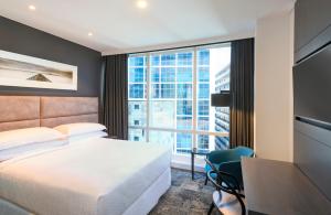 オークランドにあるフォー ポインツ バイ シェラトン オークランドのベッド、デスク、窓が備わるホテルルームです。