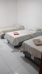 2 Betten in einem Zimmer mit weißen Wänden in der Unterkunft POUSADINHA LITORAL in Mucuri