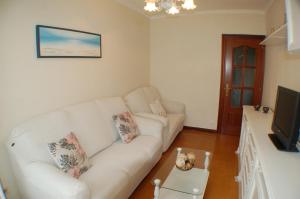 Apartamento La Luz de Reinosa 1 في رينوسا: غرفة معيشة مع أريكة بيضاء وتلفزيون