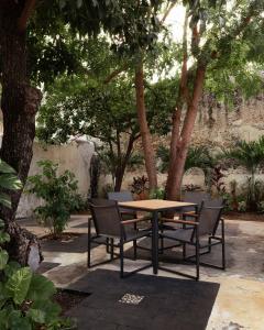 a table and chairs with a table and trees at Casa Lilia, ubicada en el Centro Histórico in Campeche