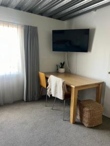 um quarto com uma mesa de madeira e uma televisão na parede em Downtown B&B em Mount Maunganui