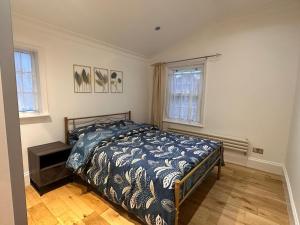 sypialnia z łóżkiem z niebieską kołdrą i 2 oknami w obiekcie Cosy home in Greenwich w Londynie