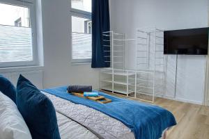 um quarto com uma cama com lençóis azuis e uma televisão em No.1 by 21Apartments em Krefeld