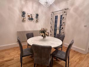 a dining room table with chairs and a vase of flowers at Cosy home in Greenwich in London