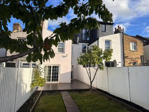 a white fence in front of a house at Cosy home in Greenwich in London