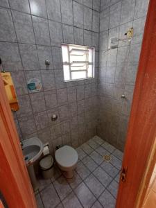 a bathroom with a toilet and a sink and a window at Hotel Mar de Minas in Três Marias