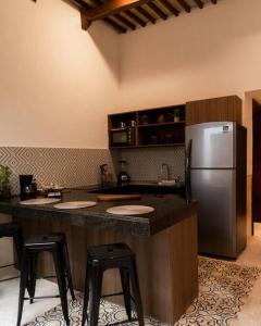 a kitchen with a counter with a refrigerator and stools at Casa Lilia, ubicada en el Centro Histórico in Campeche