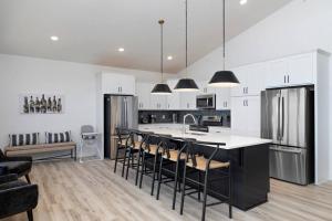 a kitchen with white cabinets and a black island with bar stools at Moonstone Lodge Lake Views Sleeps 28 GolfSim Pup Friendly in Branson +14 photos