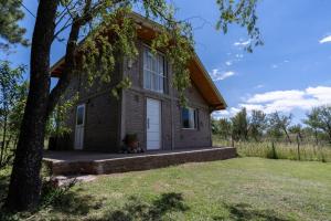 a small brick house with a white door at Chalet y Cabaña de montaña Esmeralda in Villa del Dique
