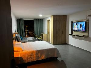 um quarto com uma cama e uma televisão de ecrã plano em Hospedajes Silk Road em Tuluá