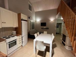 eine Küche mit einem Tisch und einem weißen Tisch und Stühlen in der Unterkunft Villa IRIS 3, Himos in Jämsä