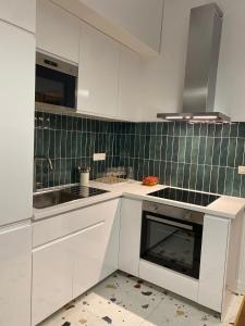 a kitchen with white cabinets and a sink at La Halte des Arènes de Nîmes Appartement de charme Terracotta in Nîmes