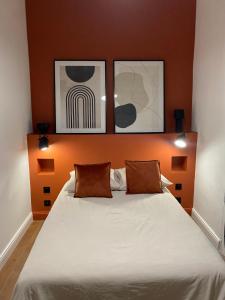 - une chambre avec un lit et deux photos au-dessus dans l'établissement La Halte des Arènes de Nîmes Appartement de charme Terracotta, à Nîmes
