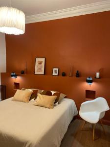 a bedroom with a large bed and a white chair at La Halte des Arènes de Nîmes Appartement de charme Terracotta in Nîmes