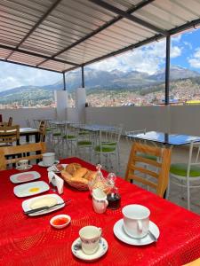 a table with a red table cloth with cups and plates at Hotel Los Pajonales in Huaraz