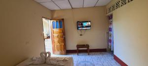 Habitación con TV en la pared y puerta en Hospedaje y Restaurante la cocina de Mami, en Moyogalpa