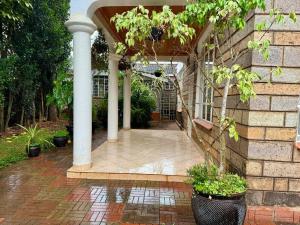 a porch of a house with columns and plants at Charming Retreat in Garden Estate-Thome, Thika Rd in Nairobi