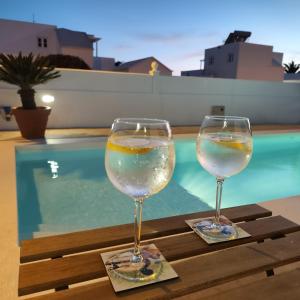 two wine glasses sitting on a table next to a swimming pool at Casa Natalia in Tías