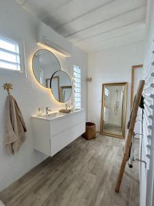 uma casa de banho branca com um lavatório e um espelho em Villa Monica, maison idéale avec enfants em Saint-François