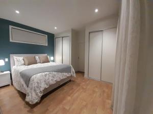 1 dormitorio con cama y pared azul en The Tiny Abode, en Snells Beach