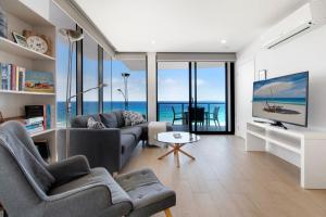 a living room with a couch and a table and some windows at Ocean Views Apartment with Rooftop Pool in Gold Coast