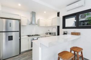 a white kitchen with a refrigerator and two chairs at Stunning 4br - Rooftop Pool, 5 mins to beach in Tulum