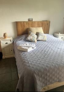 uma cama com uma cabeceira em madeira e 2 almofadas em Casa La Quinta - Tiny House em San Carlos de Bariloche