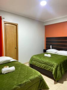 1 dormitorio con 2 camas con sábanas verdes y paredes de color naranja en Hotel Los Pajonales, en Huaraz