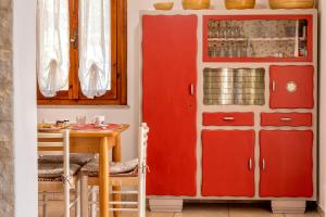 a dining room with red cabinets and a table at Domo Anghèleda - Detached with large garden in a relaxing environment, a few minutes from the sea in Alghero