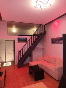 ein Wohnzimmer mit einem Sofa und einer Treppe in der Unterkunft Grand studio avec mezzanine in Voiron