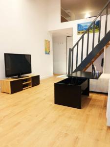 ein Wohnzimmer mit einem Flachbild-TV und einer Treppe in der Unterkunft Grand studio avec mezzanine in Voiron