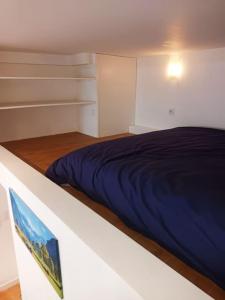 Schlafzimmer mit einem Bett mit blauer Bettwäsche in der Unterkunft Grand studio avec mezzanine in Voiron