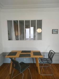 einen Holztisch mit 2 Stühlen und einem Spiegel in der Unterkunft Lumineux,chic, appartement Haussmannien de 50 m2 in Clichy