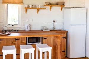 uma cozinha com um frigorífico branco e bancos brancos em Cabaña Agua de Mar em Punta Del Diablo