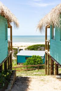 two houses on the beach with the ocean in the background at Cabaña Agua de Mar in Punta Del Diablo