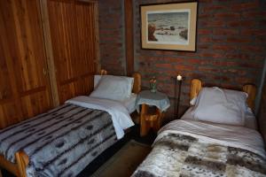 2 camas individuales en una habitación con una pared de ladrillo en Estancia La Esperanza en San Carlos de Bariloche