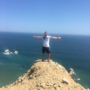 a man standing on top of a rock near the ocean at Ica adventures out of the woods in Ica