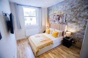 a bedroom with a bed with yellow pillows and a window at Luxury Fulham 3 bedroom Garden House in London