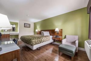 Habitación de hotel con cama y silla en Econo Lodge Atlanta Airport East, en Forest Park