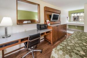 Habitación de hotel con escritorio, ordenador y TV. en Econo Lodge Atlanta Airport East, en Forest Park