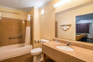 bagno con lavandino, servizi igienici e specchio di Rodeway Inn & Suites Fort Jackson a Columbia